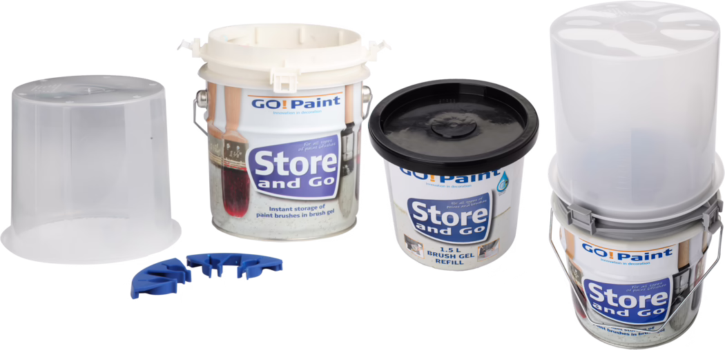 Vier Aufbewahrungsbehälter und Zubehör für Pinsel aus dem 'GO! Paint' Store and Go Pinselgel-System auf weißem Hintergrund. Das Set umfasst einen offenen Metalleimer mit weißer Kunststoffeinsatz, einen vormontierten Eimer mit transluzentem Innenbehälter und Metallbügel, einen kleinen 1,5-Liter-Kunststoffbecher mit schwarzem Deckel (Pinselgel-Nachfüllung), zwei durchsichtige Kunststoffdeckel/-einsätze und drei kleine blaue Kunststoffhalter für Pinsel. Die Etiketten zeigen das 'GO! Paint' und 'Store and Go' Branding sowie Abbildungen von Pinseln; die Gegenstände sind nebeneinander angeordnet und mit gleichmäßiger Studiobeleuchtung fotografiert.