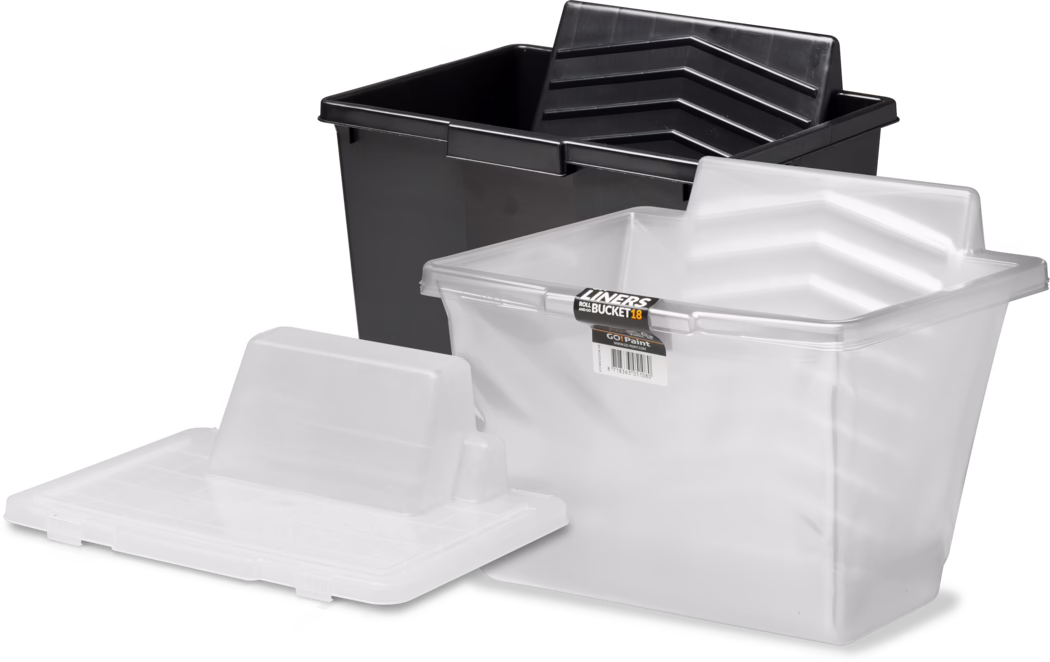 Pajarito_Dummy_Roll and Go Bucket Complett_021580_021610_021597_021616_021596_021611_2021-11 Eine Anordnung von Kunststoff-Farbwannen und Einlegeeimern: Im Hintergrund steht ein großer rechteckiger schwarzer Kunststoffeimer, im Vordergrund sind zwei halbtransparente weiße Einleger zu sehen, von denen einer teilweise im schwarzen Eimer sitzt und der andere flach liegt und eine gerippte Abtropf- und Rollenauflage zeigt. Die Einleger haben schräge, gerippte Rillen für Farbroller und eine rechteckige Ausgusskante; auf einem kleinen Etikett steht 'LINERS BUCKET 18'. Helle Studio-Beleuchtung vor weißem Hintergrund betont die glatte, glänzende Oberfläche und die geformten Details des Kunststoffs.