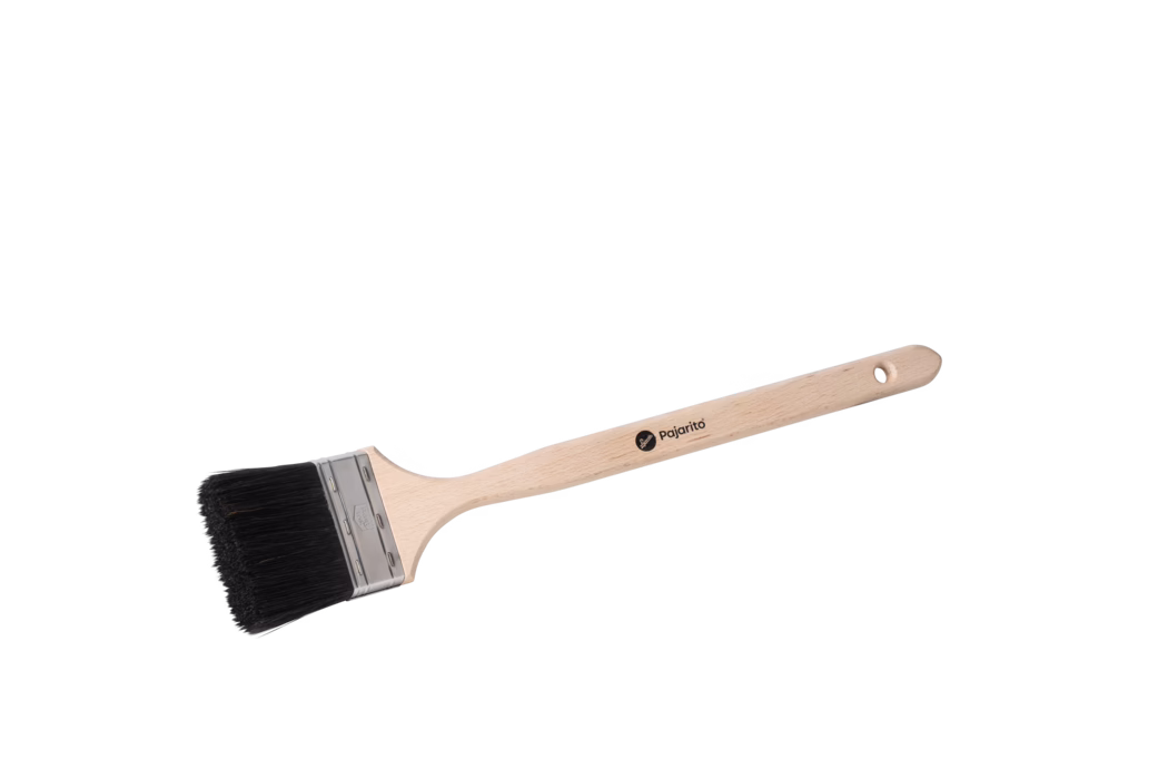 Ein Flachpinsel auf weißem Hintergrund. Er verfügt über einen langen, glatten, hellen Holzgriff mit einem runden Aufhängeloch am Ende und dem aufgedruckten Markennamen 'Pajarito'. Eine Metallzwinge hält dichte, gerade schwarze Borsten; der Pinselkopf ist rechteckig und leicht zum Griff hin geneigt. Der Pinsel liegt diagonal von links unten nach rechts oben, gleichmäßig beleuchtet und ohne weitere Gegenstände.