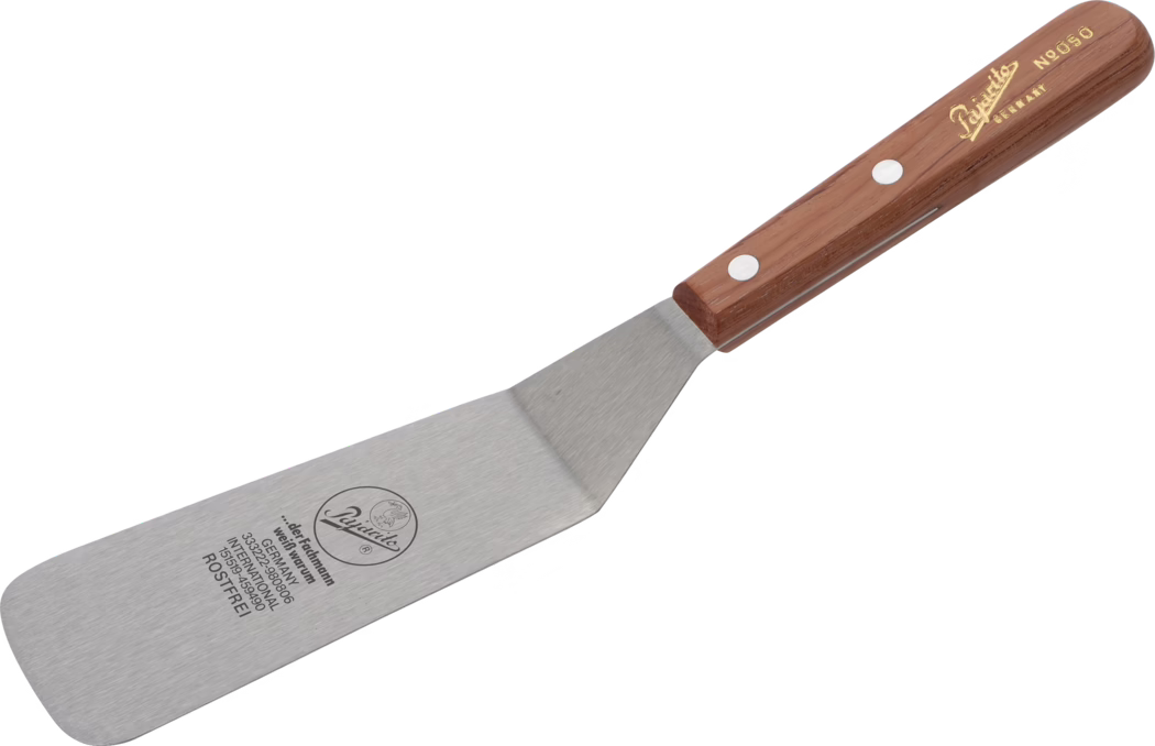 Close-up product-style photograph of a stainless-steel kitchen spatula with a long, flat, slightly rounded rectangular blade and an angled neck connecting to a riveted wooden handle. The brushed metal blade bears black printed markings, including a circular logo and several lines of text, one of which reads 'ROSTFREI'. The dark brown wooden handle has two visible metal rivets and gold-foil script lettering near the butt. The spatula is isolated on a white background and shown diagonally, highlighting the metal texture, the smooth rounded blade edge, the angled transition to the handle, and the ergonomic tapered handle shape suitable for flipping and serving food. Overall the tool appears clean and new, designed for general kitchen use.