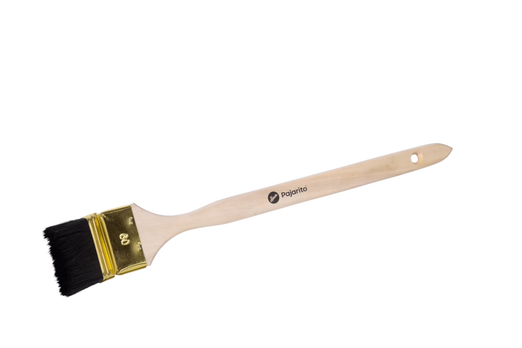 Flacher Pinsel mit hellem Holzgriff, schwarzen Synthetikborsten und goldener Metallzwinge auf weißem Hintergrund; am Griff befindet sich ein kleines 'pajarito'-Logo und ein Loch zum Aufhängen.