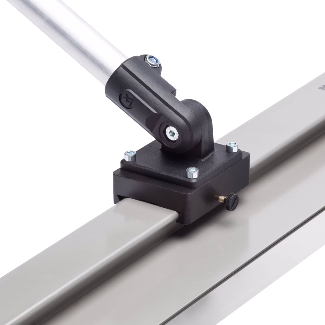 Pajarito_Dummy_Joint set quick holder smoothing spatula_159967_2021-03 Nahaufnahme einer Metallbefestigung, die an einer quadratischen Aluminium-Schiene eingespannt ist. Die schwarze Kunststoffhalterung ist mit vier sichtbaren Sechskantschrauben befestigt und hält über ein Schwenkgelenk mit einer Sechskantschraube eine schräg gestellte silberne Rohrstange. Eine kleine geriffelte Spannschraube ragt seitlich aus der Halterung. Die Schiene und Bauteile haben eine matte graue Oberfläche vor weißem Hintergrund.