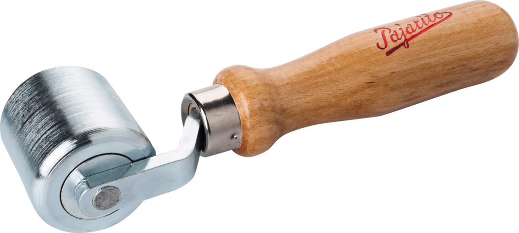 Close-up of a handheld seam roller with a short, cylindrical metal roller and a turned light-brown wooden handle. The roller is made of polished, slightly textured steel with faint machining marks; it is mounted on a small chromed metal yoke that pivots into a metal ferrule connecting to the handle. The wooden handle is varnished and ergonomically shaped with a rounded end; a red script logo is printed near the handle's top. The tool is photographed isolated on a white background with even lighting, showing surface details, reflections and the connection between roller and handle; it is typically used for pressing seams and smoothing materials such as wallpaper, vinyl or leather.